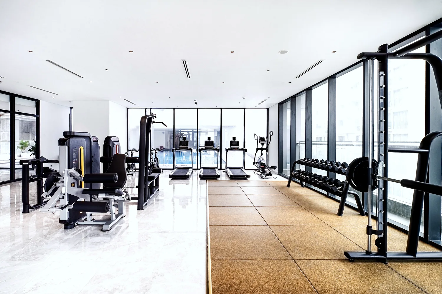 Fitness gym with cardio and weight machines beside floor-to-ceiling windows at Maison D’Rose Đà Nẵng