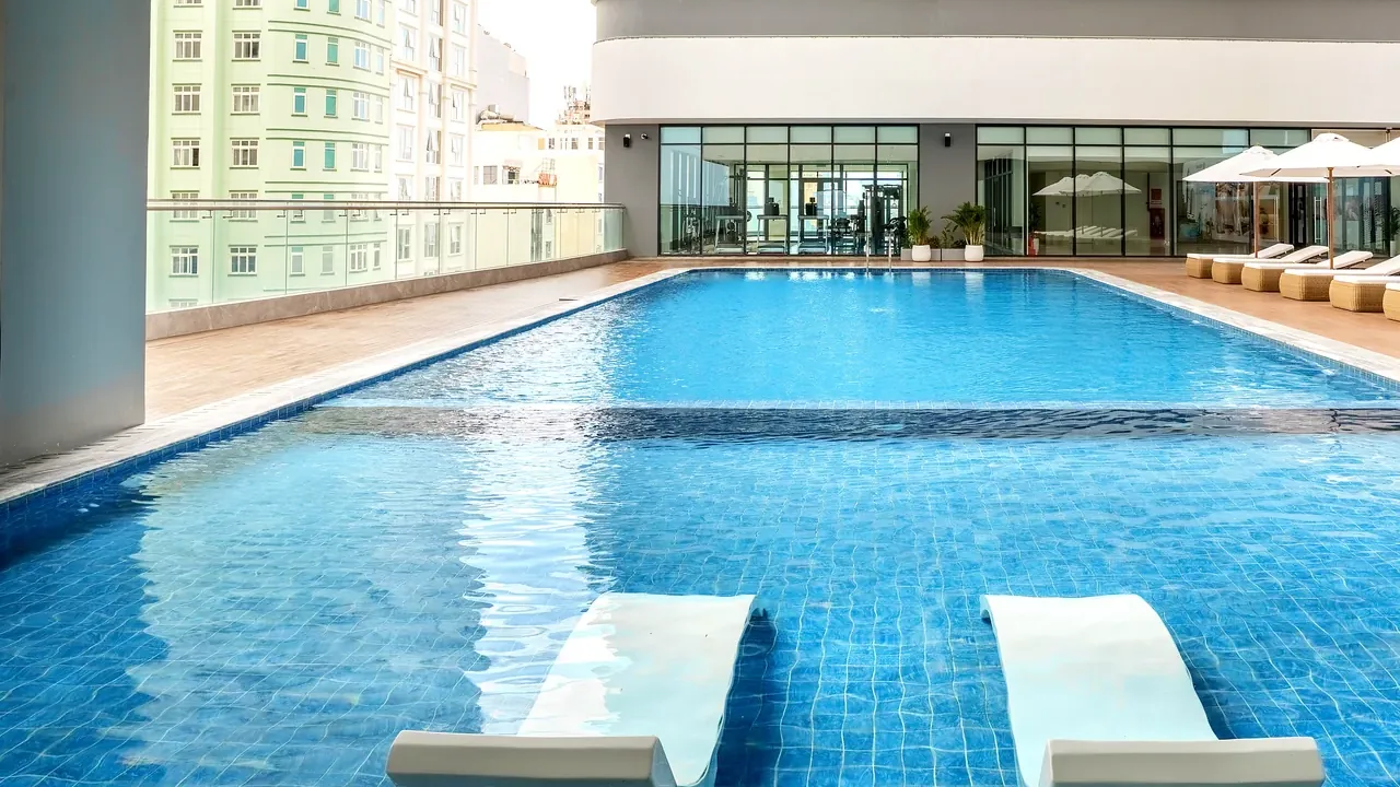 Swimming pool with tiled turquoise water and deck loungers at Maison D’Rose Đà Nẵng