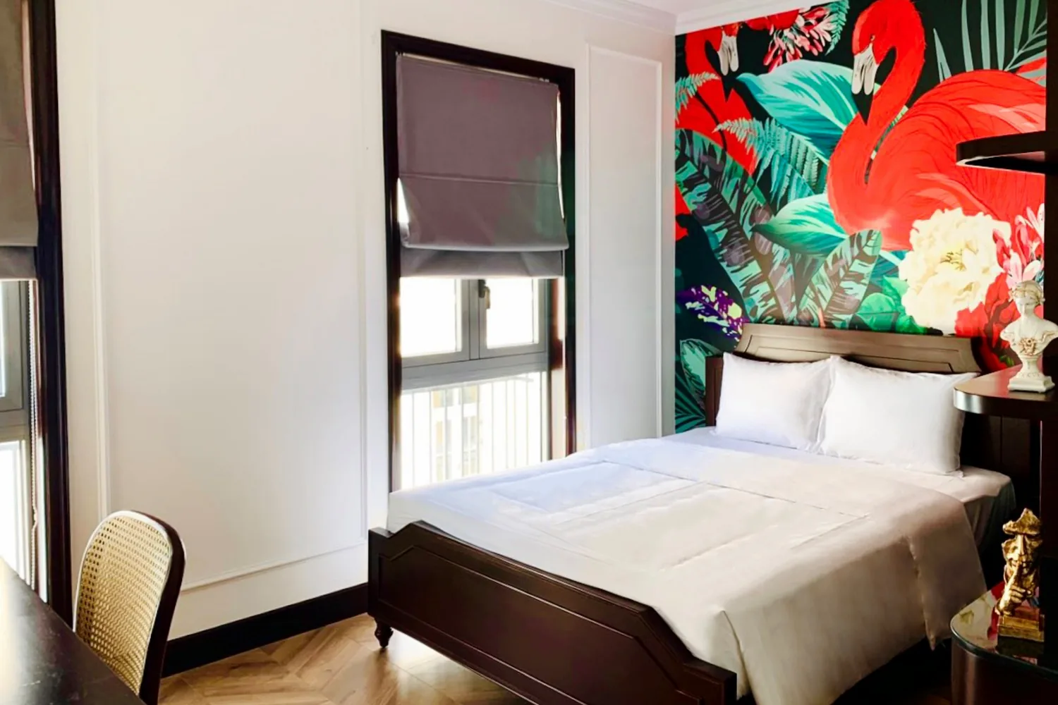 Family Room bedroom with a vivid hand-painted flamingo and tropical-foliage mural headboard above a dark-wood bed