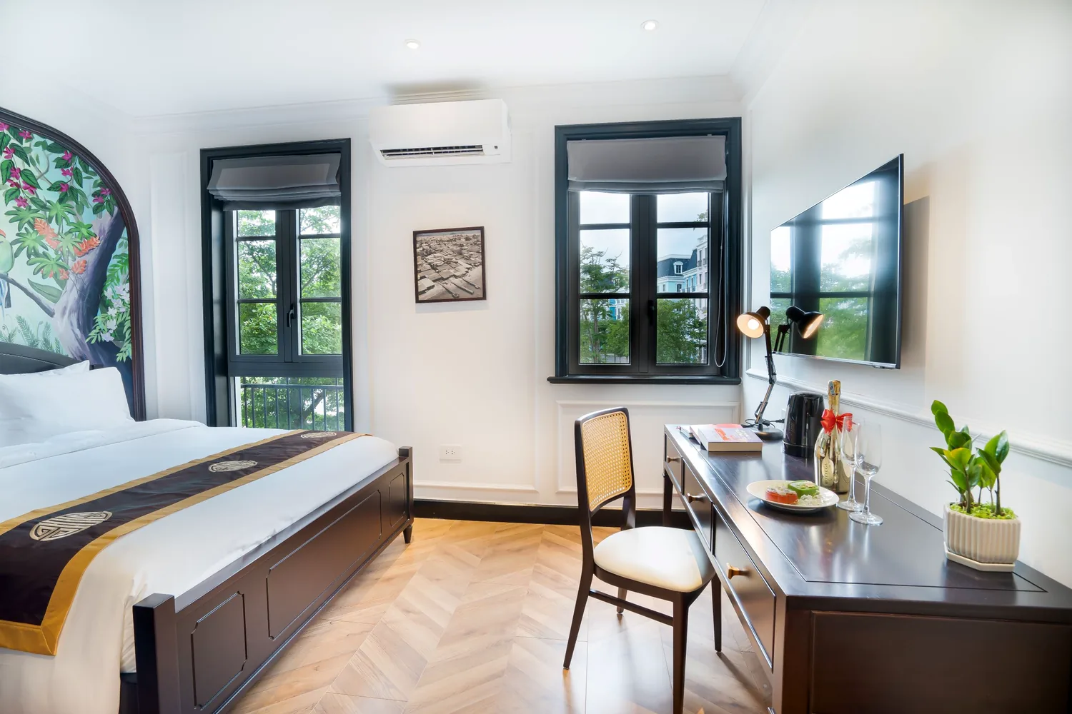 La Rose Luxury room with a dark-wood writing desk, welcome champagne and herringbone parquet beside garden-view French windows