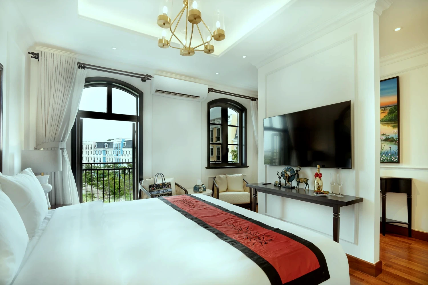 La Rose Suite with arched French windows, a red-and-black bed runner and a sitting corner